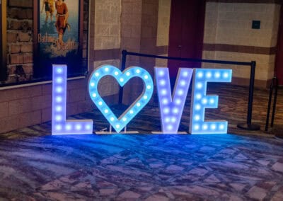 Large illuminated letters spelling LOVE with a heart-shaped O, placed indoors and lit with blue lights.